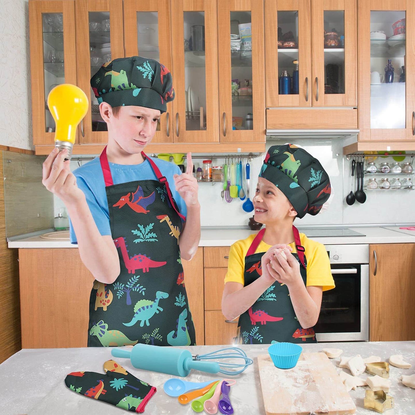Kids in cooking set showing creative play in the kitchen, with dinosaur themed apron and hat.