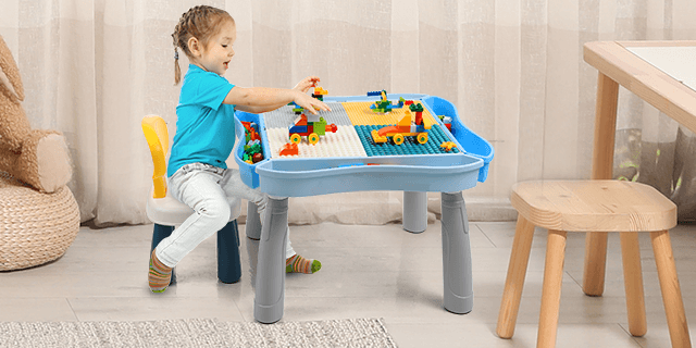 A girl happily using the Kids Activity Table and Chair Set with 320Pcs Building Blocks for creative play.